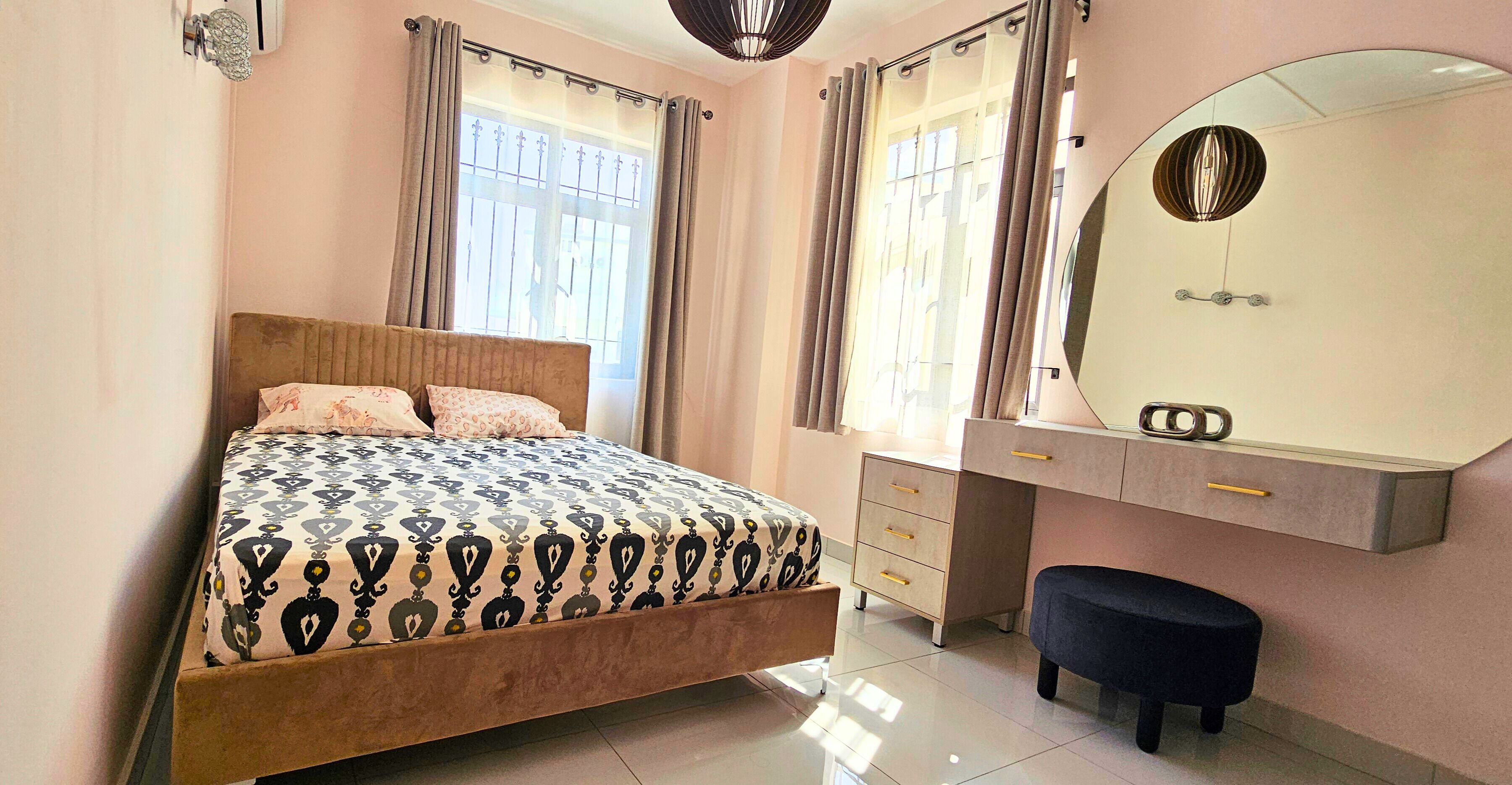 A bedroom with a bed, a dresser, a mirror, and a bench.