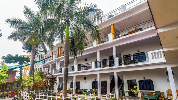 Un edificio de varios pisos con balcones, mobiliario exterior y palmeras.