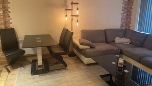 A modern living room with a dining table, sofa, and a unique brick accent wall. - Whitworth Street Apartment in Manchester (Manchester)