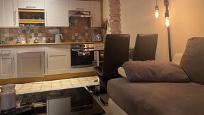 A modern kitchen with white cabinets, a brick accent wall, and a dining area with a brown sofa. - Whitworth Street Apartment in Manchester (Manchester)