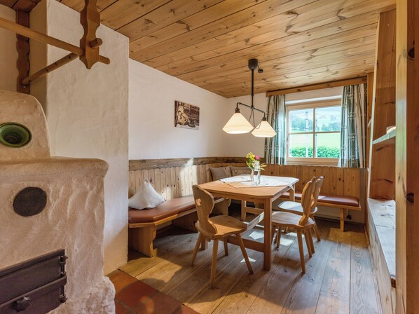 A rustic wooden interior with a wooden table, benches, and a fireplace.