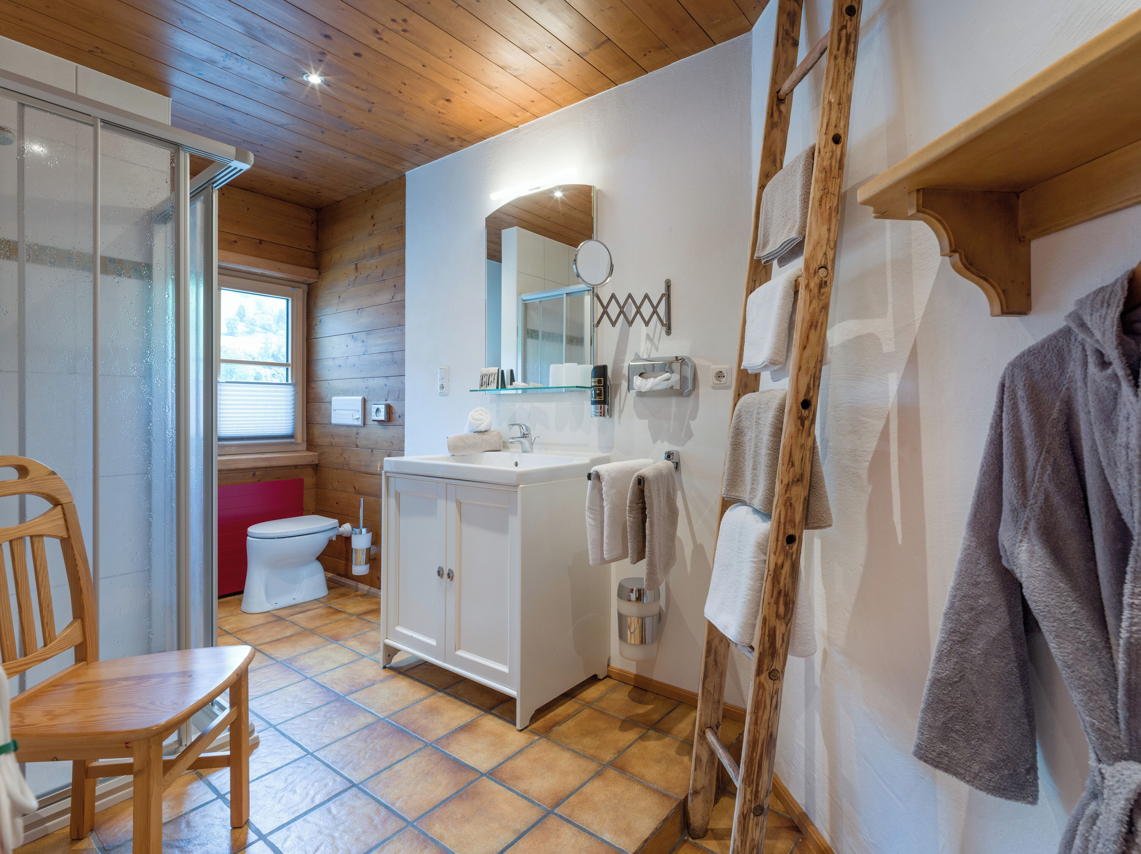 Ein Badezimmer mit Holzboden, weißen Schränken, einem Waschbecken und einem Spiegel.