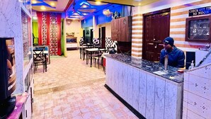 Un restaurante con mostrador, mesas e iluminación azul en el techo.