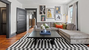 Un salon moderne avec un canapé, une table basse et des œuvres d’art accrochées au mur.