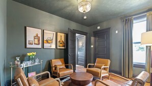Une pièce avec une table basse ronde en bois, entourée de fauteuils en cuir, un lustre et des œuvres d’art accrochées au mur.