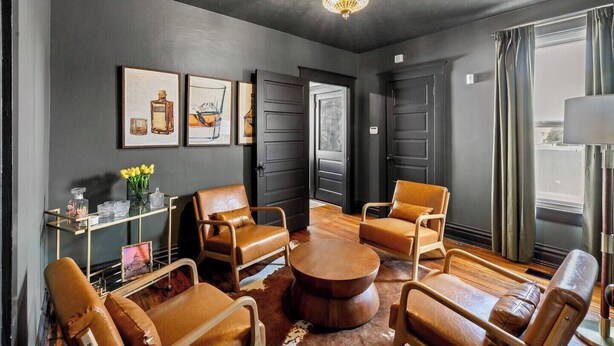 Un salon moderne avec des fauteuils en cuir, une table basse ronde et des œuvres d’art accrochées aux murs.
