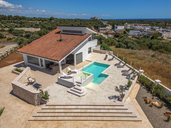 Una casa moderna con piscina, mobiliario exterior y vistas del paisaje circundante.