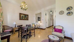 Un vaste salon comprenant un coin repas, un lustre et des assiettes décoratives accrochées au mur.