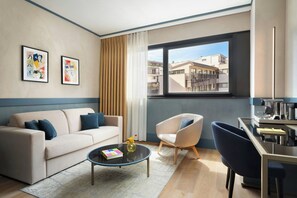 A modern living room with a sofa, armchairs, a coffee table, and a view of the city through a large window. - NEMI, Milan, a Tribute Portfolio Hotel (Milan)