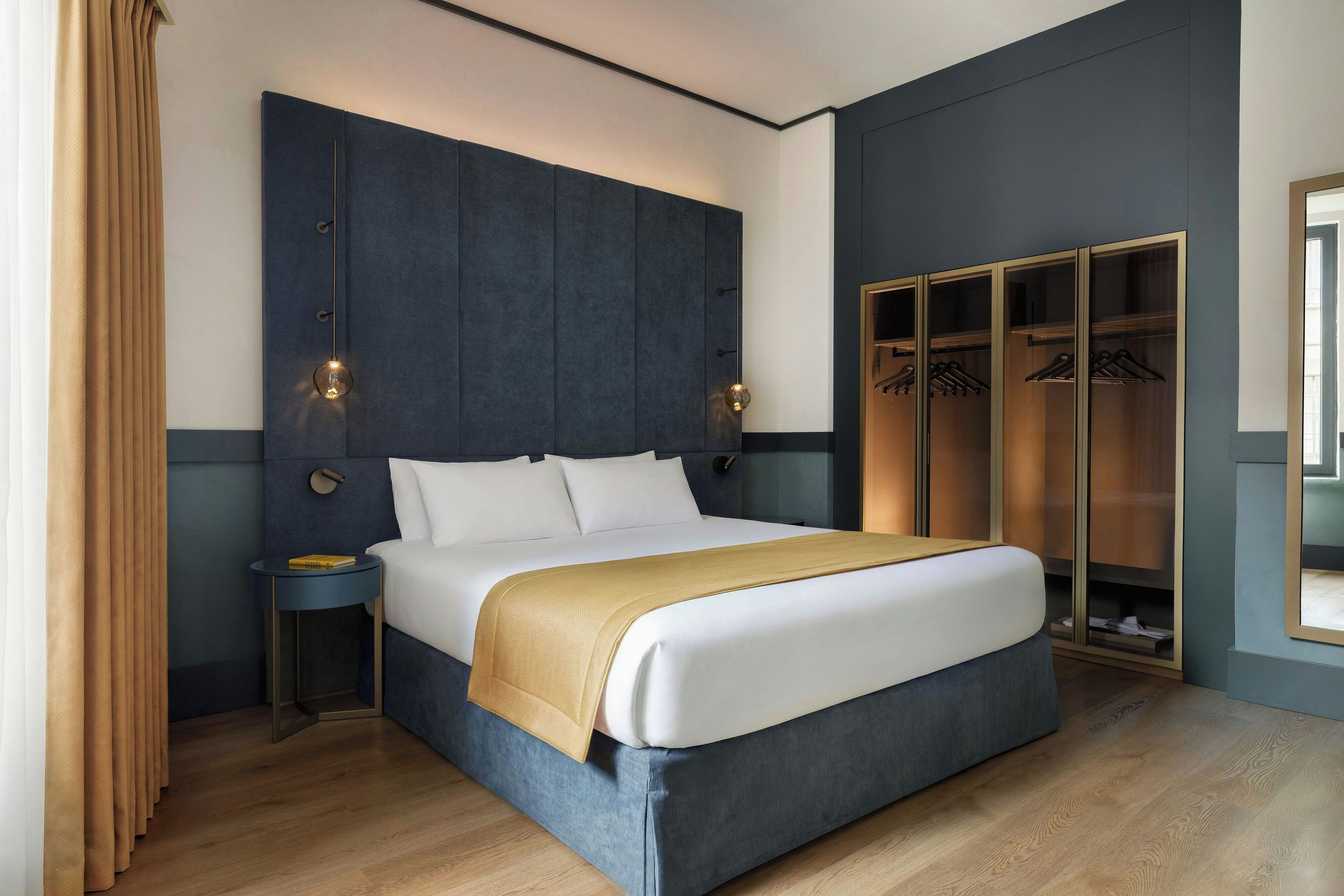 Un dormitorio moderno con una cama grande, mesitas de noche, un armario y un espejo.