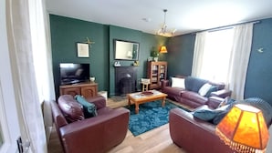 Una sala de estar con chimenea, televisor y sofá.
