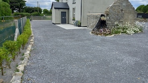 Una casa con camino de grava, un muro de piedra y un pequeño jardín con flores blancas.
