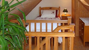 A cozy attic bedroom with a wooden bed, a nightstand, a lamp, and a wooden dresser. - Bridies Holiday Cottage Roundstone (Inishnee)