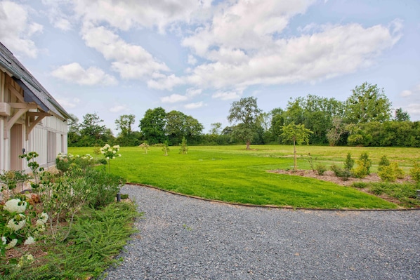 A house with a gravel driveway leading to a well-maintained lawn and trees in the background.