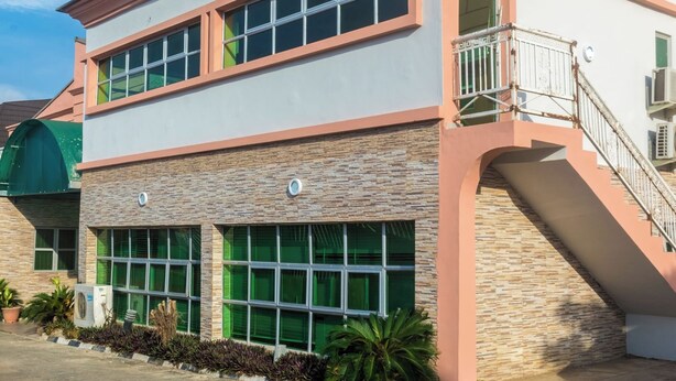 A two-story building with a flat roof, large windows, and a staircase leading to an upper level. - Bliss World Resorts & Hotels (Akure)