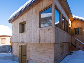 A wooden cabin with a snow-covered roof, large windows, and a wooden staircase leading to the entrance. - 2-room apartment for 6, pets allowed, terrace (Valloire)