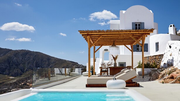 Un área de piscina moderna con una pérgola de madera, paredes blancas y vistas despejadas del paisaje circundante.
