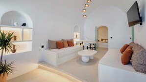 Una sala de estar moderna con un sofá blanco, una mesa de centro y un televisor montado en la pared.