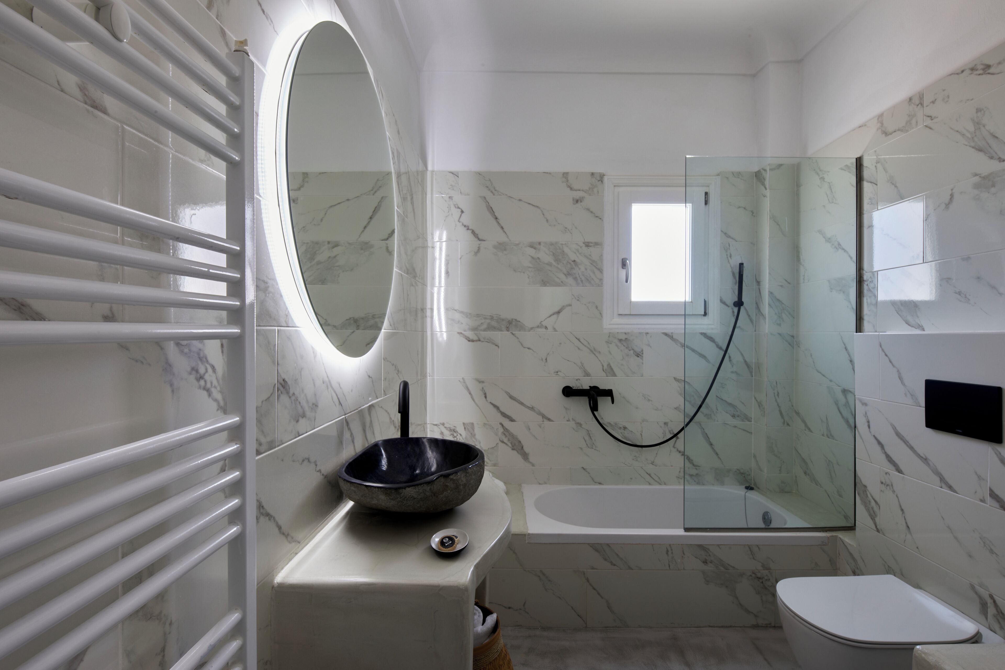 Une salle de bain moderne avec un lavabo en marbre, une baignoire et une douche à parois de verre.