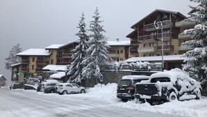 Un edificio cubierto de nieve con varios balcones y un gran árbol en primer plano.