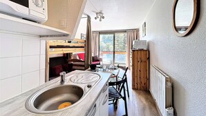 A compact kitchen with a sink, stove, and dining area. - Bright Studio 4 pers, Ski-in/Ski-out, Pets allowed (Le Corbier)