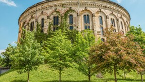 Un bâtiment historique à la façade circulaire, doté de fenêtres en arc de cercle et d’une façade en pierre.