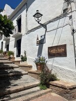 Un edificio con un letrero que dice "Castillo Arabe", que presenta un estilo arquitectónico tradicional con paredes blancas y escalones de terracota.