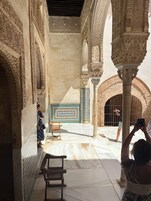Un patio interior con detalles arquitectónicos intrincados, un banco y una persona tomando una fotografía.