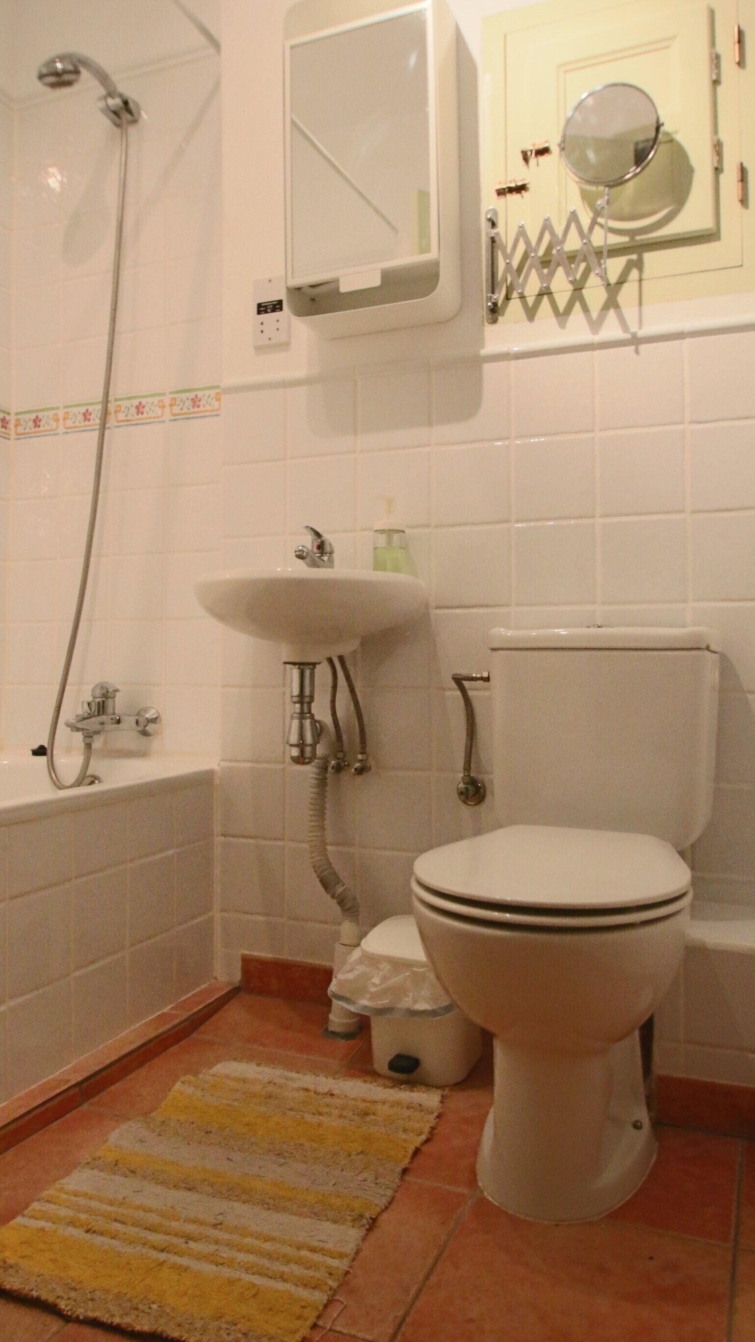 Un baño con bañera, lavabo, inodoro y espejo sobre el lavabo.