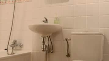 Un baño con bañera, lavabo, inodoro y espejo sobre el lavabo.