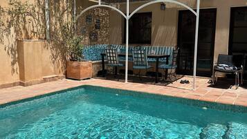 Een buitenzwembad, ligstoelen bij het zwembad