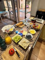 Una encimera de cocina con alimentos para el desayuno, como huevos, pan, frutas y una tabla de cortar con un tomate.
