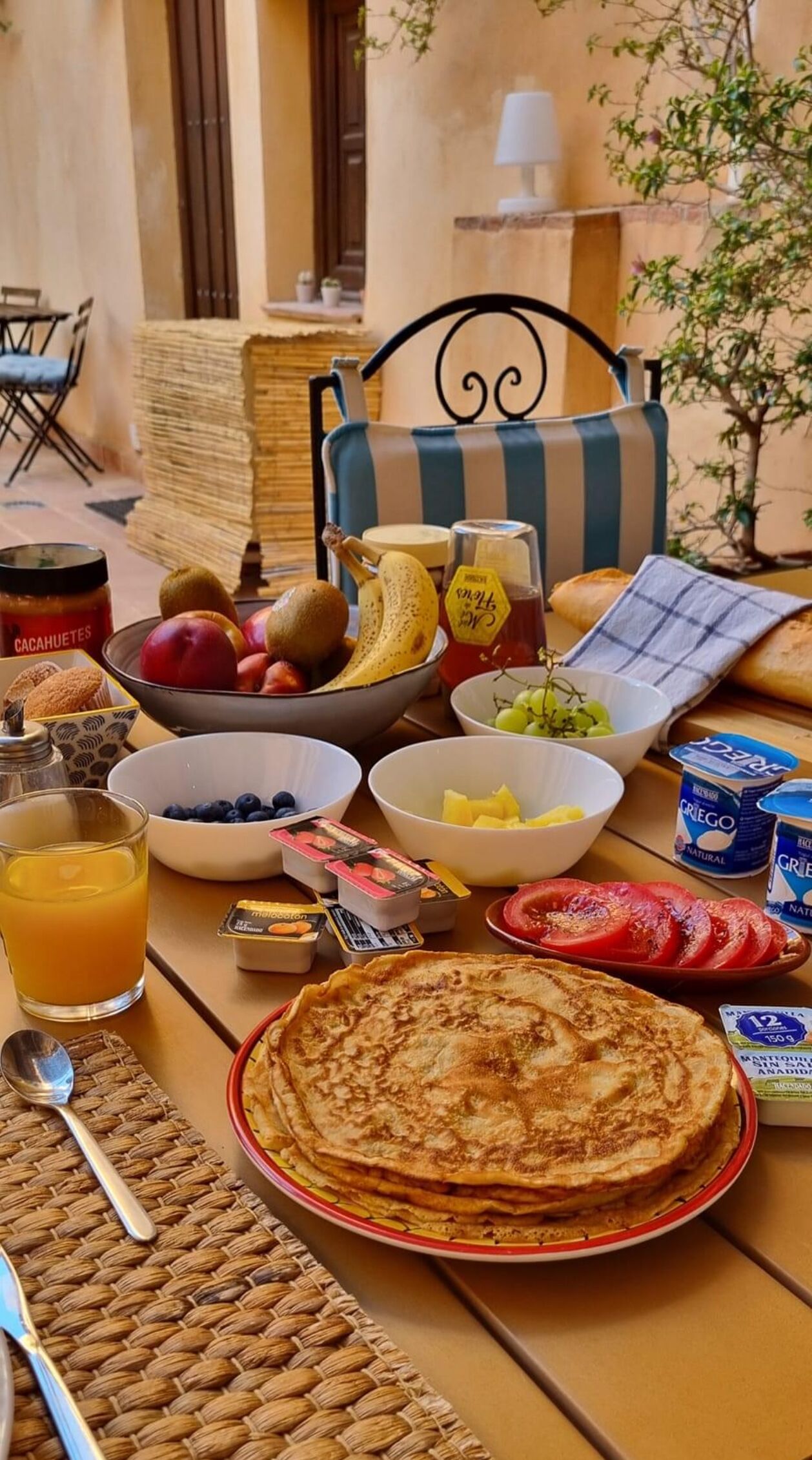 Una mesa de desayuno con diversos alimentos, como panqueques, frutas y salsas.