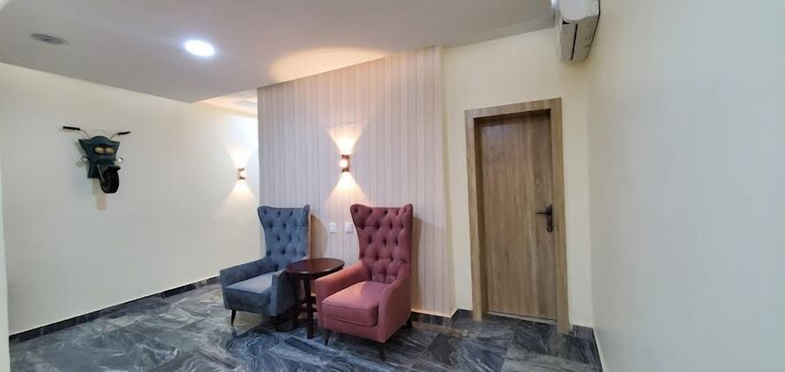 Un couloir avec deux chaises, une petite table et une porte en bois.