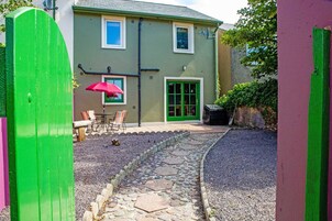 A house with a stone pathway leading to a patio with a table and chairs.