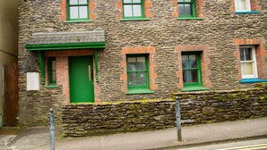 A stone building with green windows and doors, a stone foundation, and a small porch area. - Dingle Town Holiday Home (Dingle)