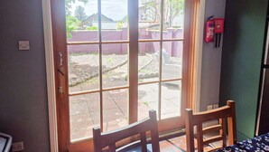 A room with a sliding glass door leading to an outdoor area, a wooden chair, and a fire extinguisher mounted on the wall. - Dingle Town Holiday Home (Dingle)
