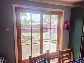 A room with a sliding glass door leading to an outdoor area, a wooden chair, and a fire extinguisher mounted on the wall.