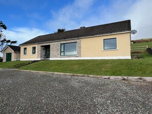 Et moderne hus med to etager, skrå tag, store vinduer og en velplejet græsplæne.