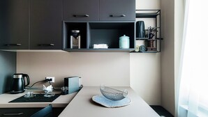 A modern kitchen with dark cabinets, a coffee maker, a kettle, and a shelf with kitchen items. - Turchese (Como)