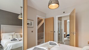 A modern hotel room with two beds, a staircase, and a large mirror. - Ger Y Mor - Village Centre With Parking (Saundersfoot)