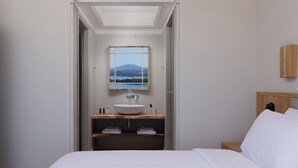 Ein modernes Badezimmer mit einem großen Bett, einem hölzernen Waschtisch und Blick auf einen Berg durch ein gerahmtes Fenster.