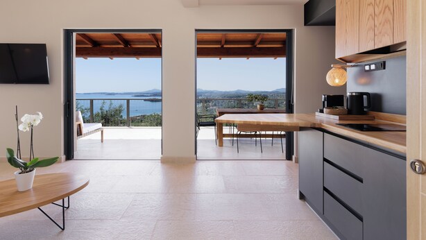 Eine moderne Küche mit Meerblick, ein Essbereich mit Holztisch und eine Orchidee im Topf.