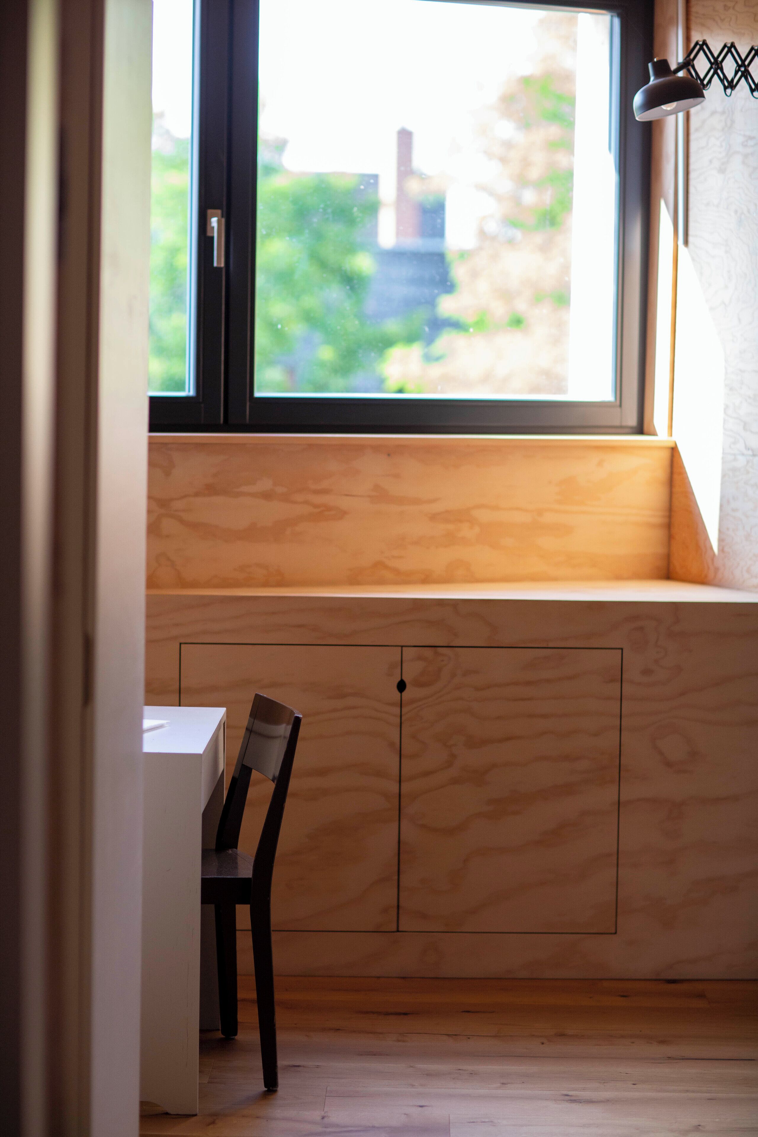 Ein Zimmer mit einer Holzbank und einem Stuhl in der Nähe eines Fensters.