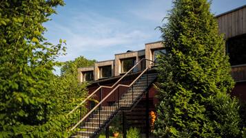 Un bâtiment moderne doté d’un escalier menant à un niveau supérieur, le tout entouré d’une végétation luxuriante.