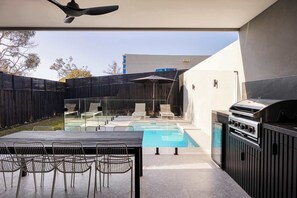 An outdoor pool area with lounge chairs and a barbecue grill.