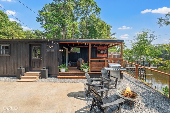 A rustic cabin with a porch, outdoor seating, and a fire pit.
