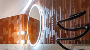 Un bagno moderno con lavabo bianco, rubinetteria dorata e uno specchio con illuminazione integrata.