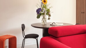 Un'elegante zona pranzo con un tavolo rotondo, un vaso di fiori, un divano rosso e una lampada a sospensione.