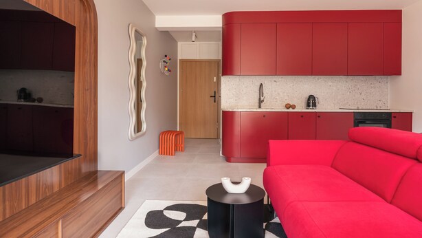 Un soggiorno moderno con un divano rosso, un tavolino nero e un mobile TV in legno.